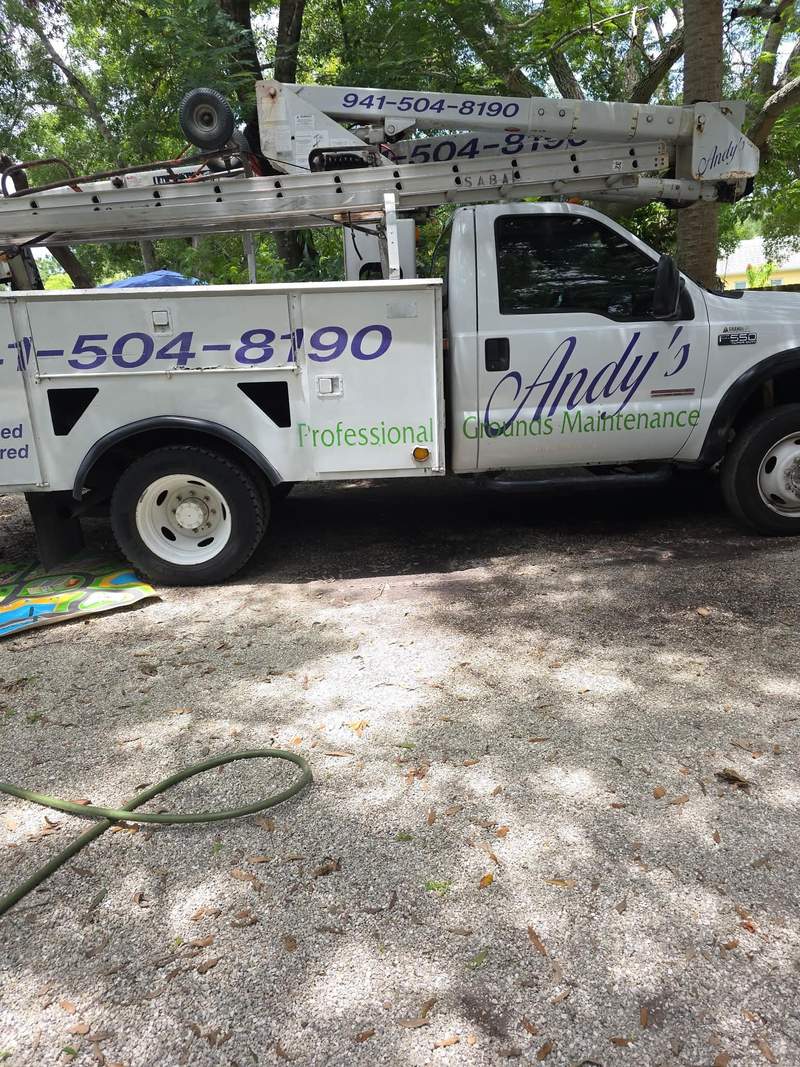 Andy's PGM bucket truck parked in the shade, the phone number painted on the side and on the boom.